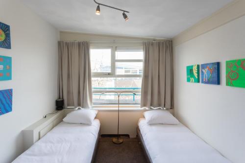 two beds in a room with a window at Hello Zeeland - Appartement Loverendale 31 in Domburg