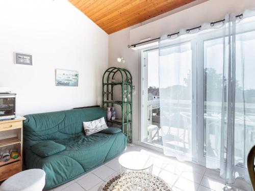Il comprend un salon avec un canapé vert et un balcon. dans l'établissement Apartment Les Fées de Mirbois by Interhome, à Vaux-sur-Mer