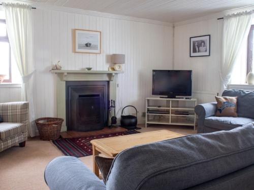 a living room with a fireplace and a tv at Holiday Home Ploughman by Interhome in Eyre