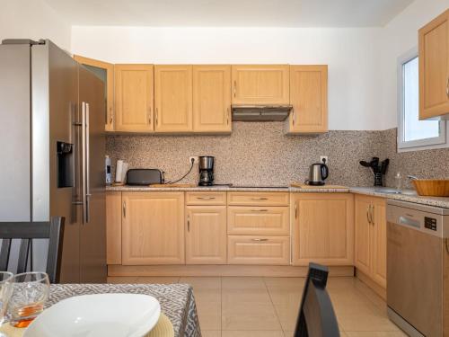 a kitchen with wooden cabinets and a table in it at Holiday Home Villa Les Treilles by Interhome in Le Racou