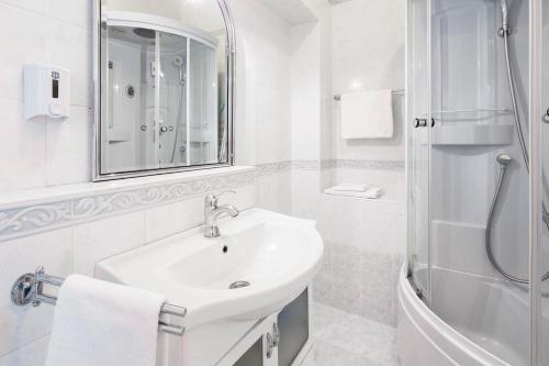 a white bathroom with a sink and a shower at Apartments Suzy in Split