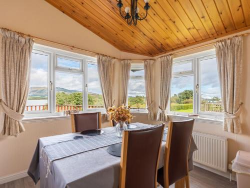 a dining room with a table and chairs and windows at Chalet Loch Side Lodge 5 by Interhome in Kinross