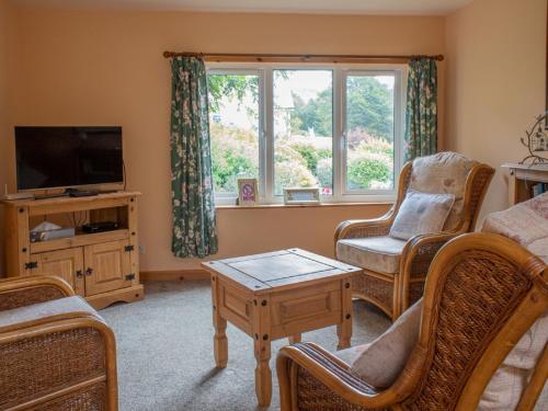 a living room with a tv and chairs and a table at Chalet Skye Garden Accommodation by Interhome in Portree