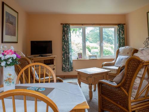 a living room with chairs and a table and a tv at Chalet Skye Garden Accommodation by Interhome in Portree