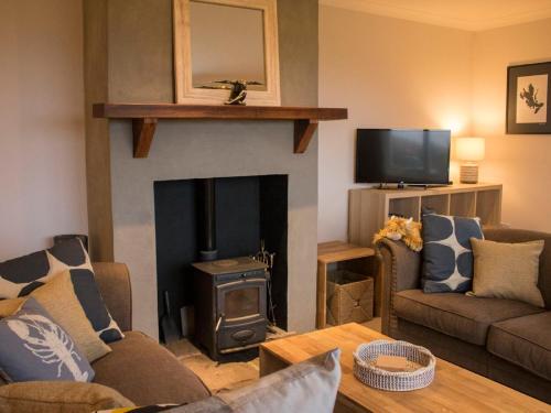 a living room with a fireplace and a tv at Holiday Home An Caladh by Interhome in Harlosh