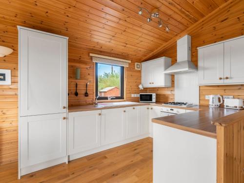 a kitchen with white cabinets and a wooden ceiling at Chalet Loch Side Lodge 8 by Interhome in Kinross