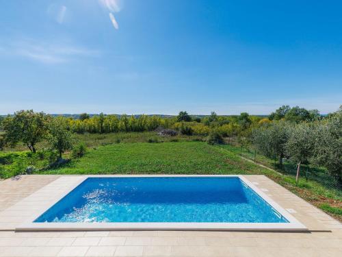 an outdoor swimming pool with a view of a field and trees at Holiday Home Villa Luna Maris by Interhome in Umag