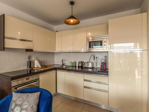 une cuisine avec des placards blancs et une chaise bleue dans l'établissement Apartment Cita Di Sali 13 by Interhome, à Porto-Vecchio