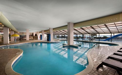 a large swimming pool in a building with benches at Breakers Tower 1BR Oceanfront Condo in Myrtle Beach
