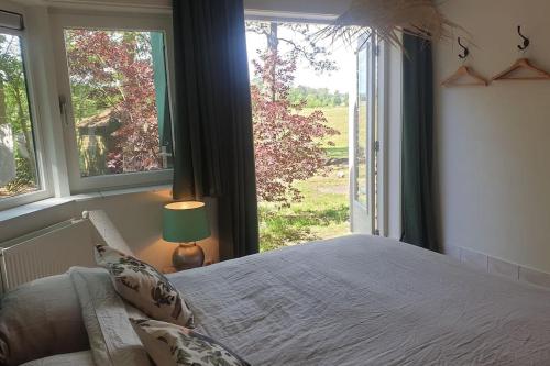 a bedroom with a bed and a large window at Boshuisje Doldersum: omheinde tuin en uniek uitzicht in Doldersum