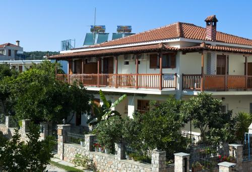 uma casa com varanda e árvores em frente em Pansion Matoula em Skiathos