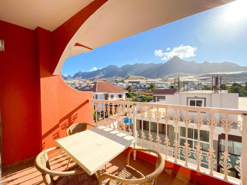a balcony with a wooden table and chairs and mountains at Hotel La Aldea Suites in La Aldea de San Nicolas