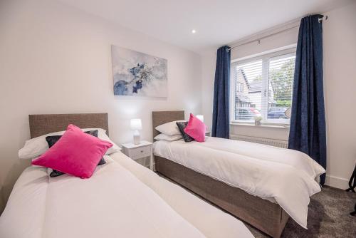 2 camas con almohadas rosas en un dormitorio en 4 Eureka Waldringfield Air Manage Suffolk, en Woodbridge