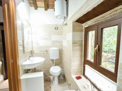 a bathroom with a toilet and a sink and a window at Holiday Home Turi by Interhome in Roccatederighi