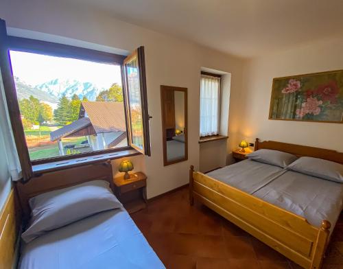 1 Schlafzimmer mit 2 Betten und einem großen Fenster in der Unterkunft Vela Ferienwohnung mit Dachterrasse in Colico