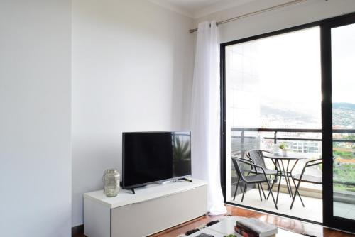 a living room with a flat screen tv on a white cabinet at Design Gardens, a Home in Madeira in Funchal