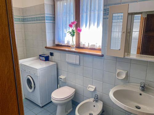 ein Bad mit einem WC, einem Waschbecken und einem Fenster in der Unterkunft Vela Ferienwohnung mit Dachterrasse in Colico