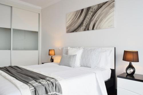 a white bedroom with a large bed and two lamps at Design Gardens, a Home in Madeira in Funchal