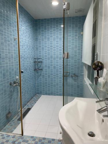 台東市的住宿－樂觀軒民宿，浴室设有水槽和蓝色瓷砖淋浴。
