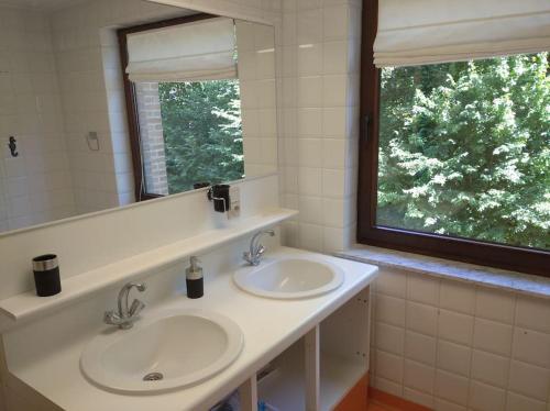 a bathroom with two sinks and a mirror and a window at 2 bedroom app, close to the beach and Plopsaland in De Panne