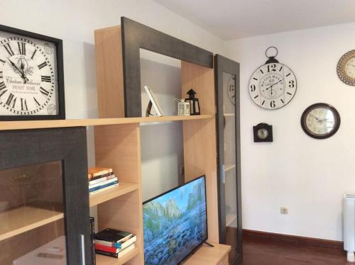 a living room with a tv and clocks on the wall at HyP - A Casa do Correo Vello 1ºA / O TEMPO in Pontevedra