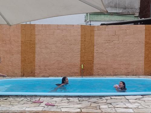 two girls are swimming in a swimming pool at Casa Bom Sossego in Boicucanga