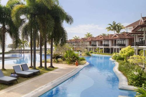 a pool at a resort with palm trees at Ramada Resort by Wyndham Kochi in Cochin