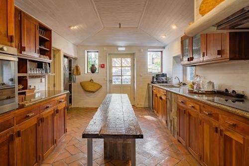 a large kitchen with wooden cabinets and a wooden table at Villa Cerrado das Fontainhas SPA in Sintra