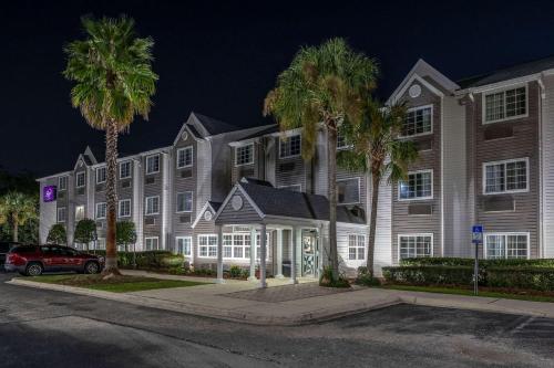 a large building with palm trees in front of it at Sleep Inn Jacksonville Airport in Jacksonville