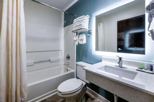 a bathroom with a toilet and a sink and a tub at Sleep Inn Jacksonville Airport in Jacksonville
