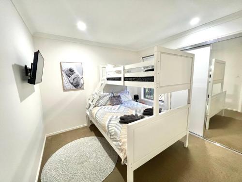 um quarto com um beliche branco num quarto em Bundys Best! Modern Luxury in the heart of town em Bundaberg