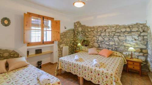 1 dormitorio con 2 camas y pared de piedra en Cuesta Blanca Montilla by Ruralidays, en Montilla