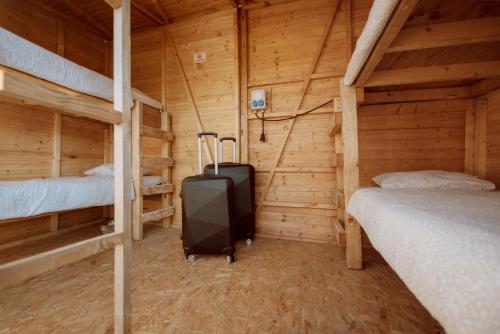 シュピールベルクにあるEvent Lodge Camping Spielbergのベッド2台とスーツケースが備わるキャビンの客室です。