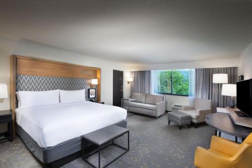 ein Hotelzimmer mit einem großen Bett und einem Wohnzimmer in der Unterkunft Holiday Inn Asheville East-Blue Ridge Pkwy, an IHG Hotel in Asheville