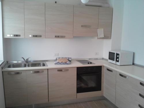 a kitchen with wooden cabinets and a sink and a microwave at Albergo Diffuso Zoncolan in Ovaro