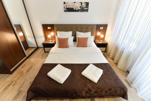 a bedroom with a large bed with two night stands at Vicos Suites in Bucharest