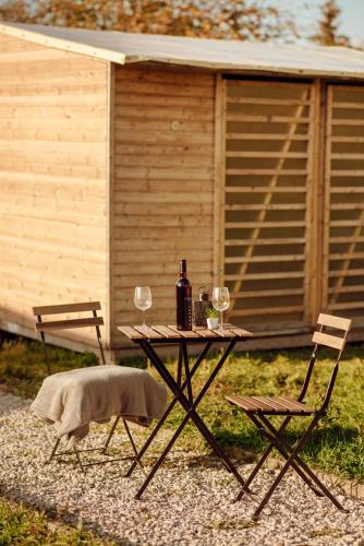 a picnic table with two chairs and a bottle of wine at Event Lodge Glamping Spielberg in Spielberg