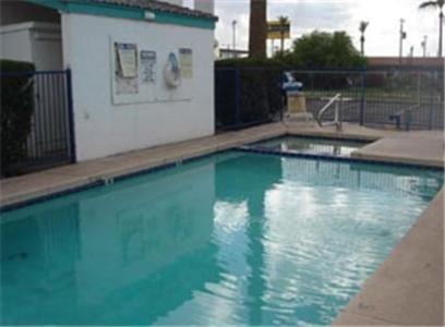 a swimming pool with blue water in front of a building at Colonade Motel Suites in Mesa