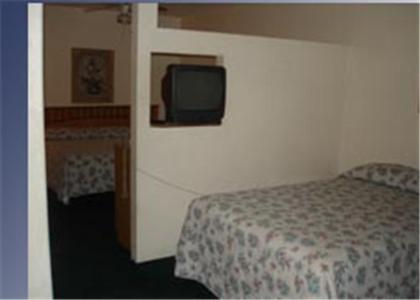a bedroom with a bed and a tv on a wall at Colonade Motel Suites in Mesa