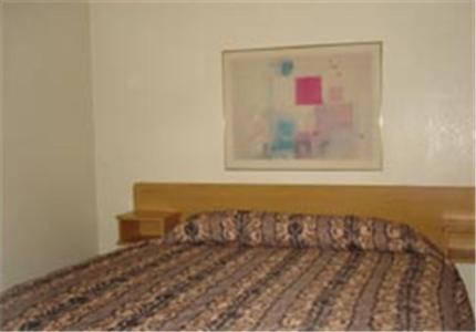 a bed in a bedroom with a picture on the wall at Colonade Motel Suites in Mesa