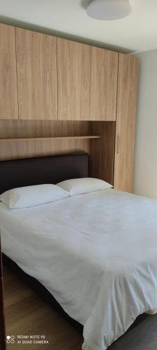 um quarto com uma grande cama branca e uma cabeceira em madeira em Bilocale 400 mt impianti sci e box auto em Pontagna