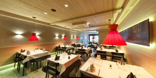 un restaurante con mesas blancas y luces rojas en Hostal Pey, en Bohí