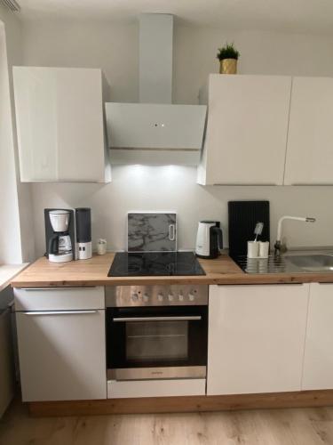 a kitchen with white cabinets and a stove top oven at Exklusives Apartment mit Schwimmbad im Allgäu in Oy-Mittelberg