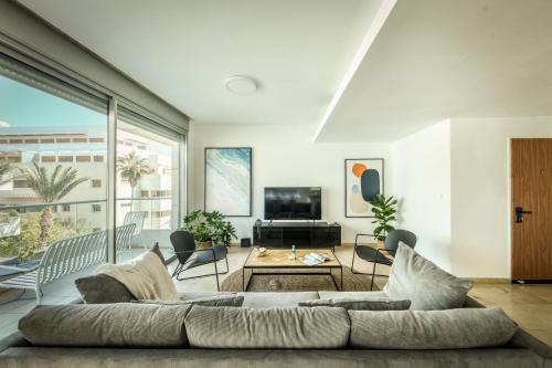 sala de estar con sofá y TV en Chic Apartment w Balcony, Mamad & Parking 3-min from Beach by Sea N' Rent en Tel Aviv