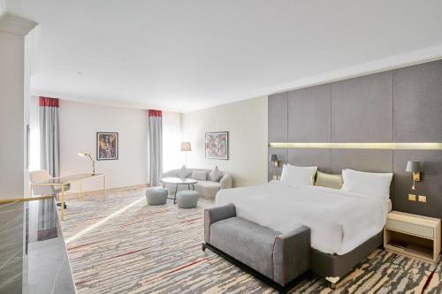 um quarto de hotel com uma cama grande e uma cadeira em Ramada by Wyndham Doha Old Town em Doha
