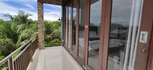 a balcony with glass doors with a view of palm trees at Eddie's Homestay in Lhonga
