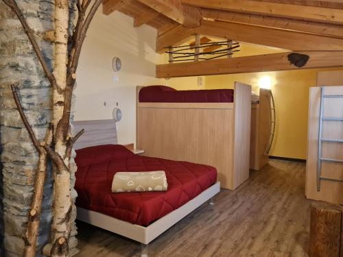 Foresteria Giardino في Paisco: غرفة نوم بسرير احمر وشجر