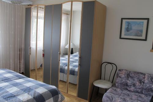 1 dormitorio con espejo, 1 cama y 1 silla en Gemütliche Ferienwohnung en Annenheim