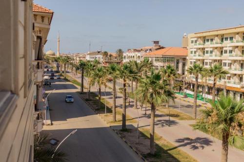 una calle en una ciudad con palmeras y edificios en El Mina City, en ‘Izbat al Burj