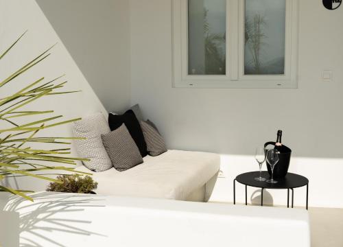 a white living room with a white couch and a plant at Nimbus Mykonos in Agios Stefanos